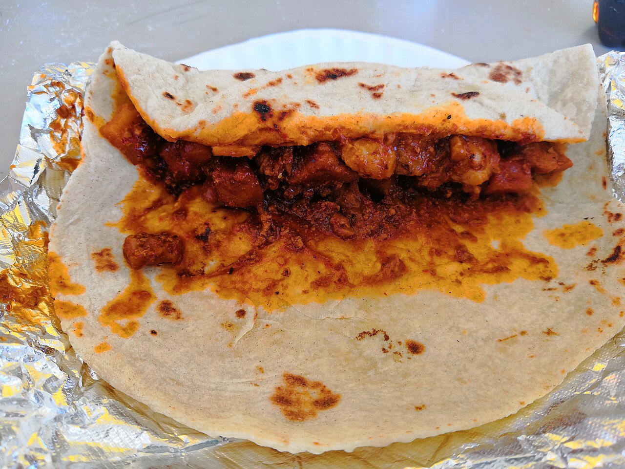 Hand-rolled burrito split open on a wooden board, pico and lime on the side