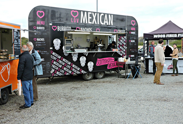 Open-front taqueria counter with grill smoke under late-afternoon light